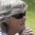 grey haired woman (head only) wearing dark glasses, looking to left